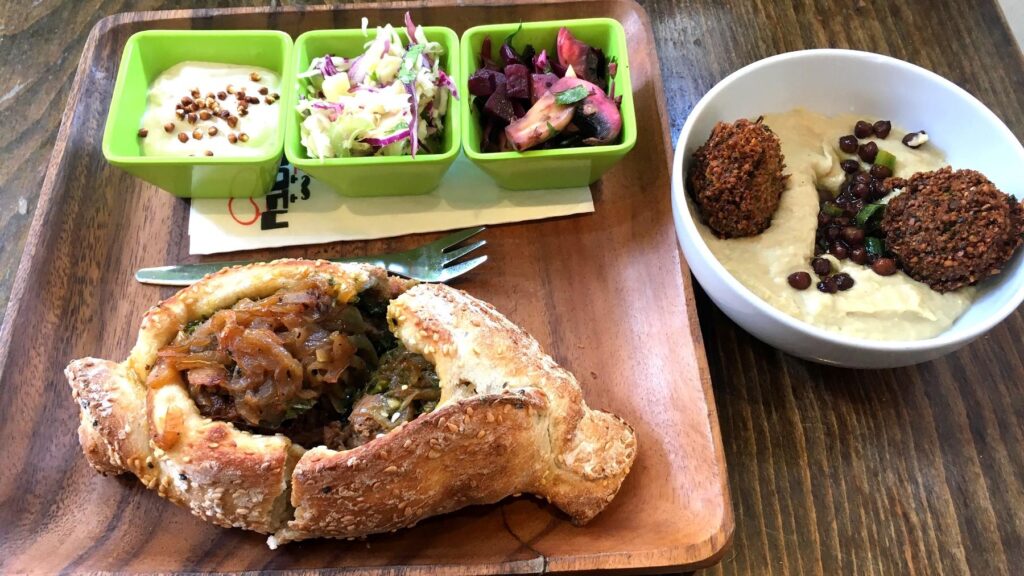 エルサレムのクルド料理。パンをくり抜いたボウルにシチューを盛り、フムスとファラフェルが添えられた一皿