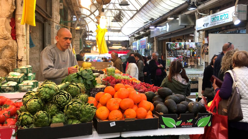 エルサレムのマハネ・イェフダ市場。アーティチョーク、オレンジ、アボカドなど新鮮な野菜や果物が並ぶ