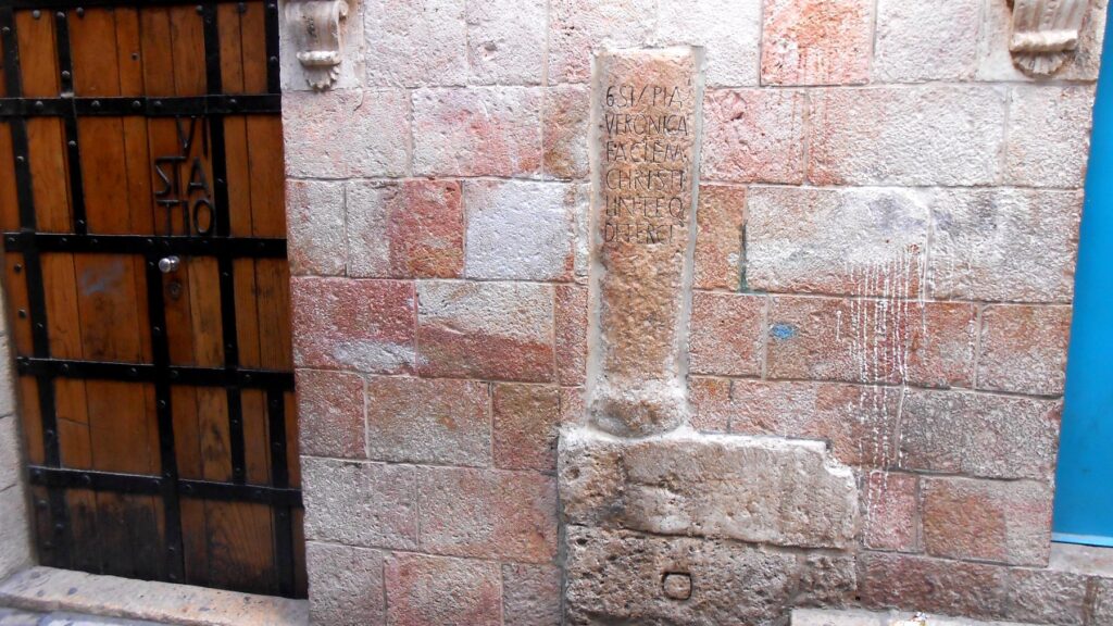 悲しみの道・第6留のベロニカのステーションを示す石柱。旧市街の石畳の路地に立つ