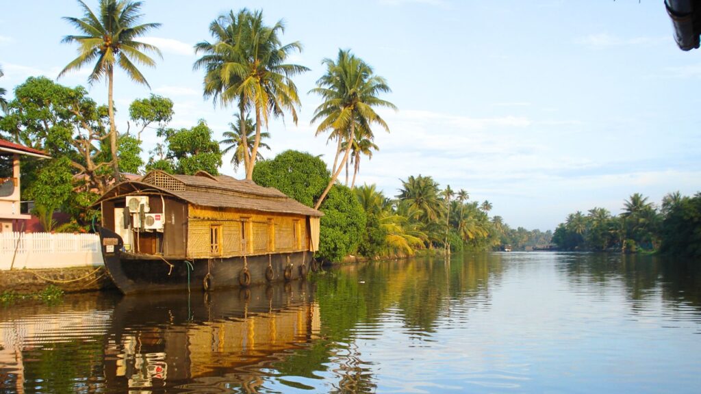 ケララのバックウォーターに浮かぶハウスボートとヤシの木の緑が水面に映る穏やかな風景