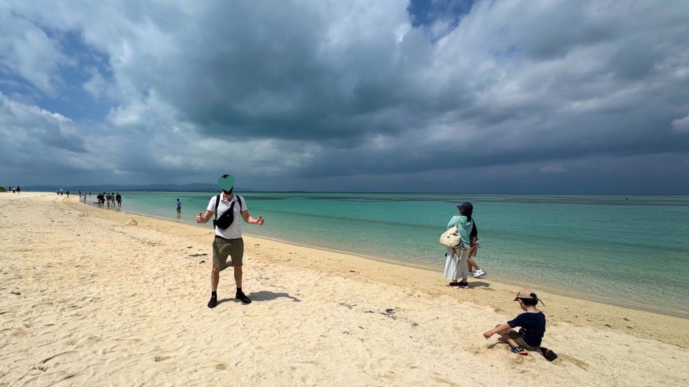 竹富島コンドイビーチの白砂と青い海。曇り空の下でのびのびと過ごす家族