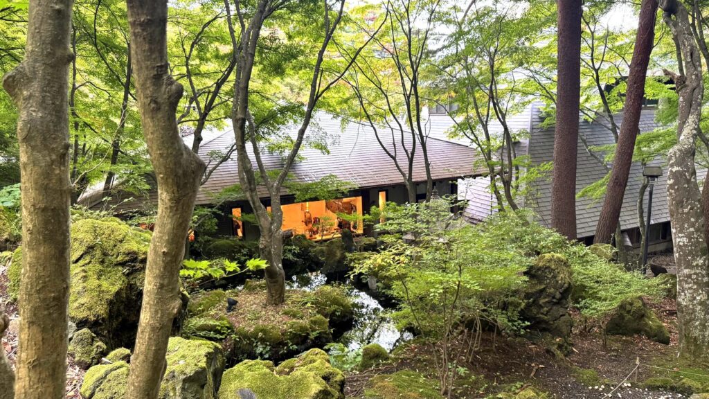 木々と溶岩石の庭園越しに見える久保田一竹美術館の建物