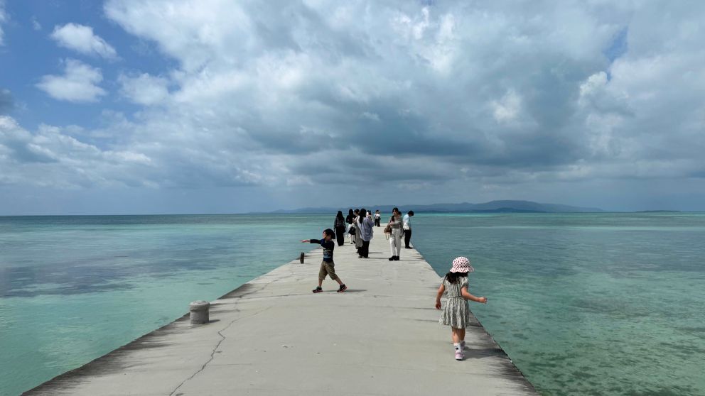 竹富島の西桟橋を歩く子どもたち。エメラルドグリーンの海が左右に広がる