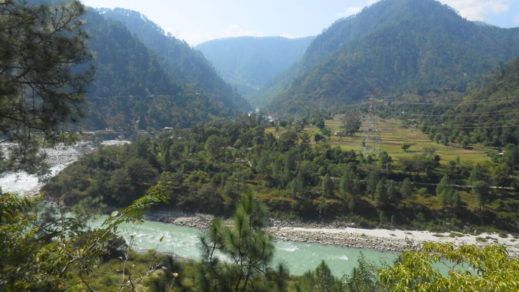 緑の山々と段々畑の間を流れるエメラルドグリーンのガンジス川上流、山間の静かな谷の風景