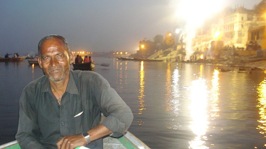 バラナシのガンジス川を夜のボートで渡る。背後に火葬場マニカルニカー・ガートの炎が揺れる