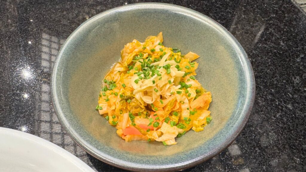 キャベツとにんじんを使ったスパイシーなピクルスの小鉢。パプリカ風味でチャイブが散らされている