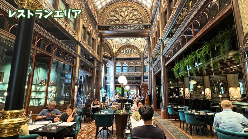パーリシ・パッセージ・カフェ&レストランのレストランエリア。賑わう店内にはアーケードの高い天井と緑のベルベットチェアが並ぶ