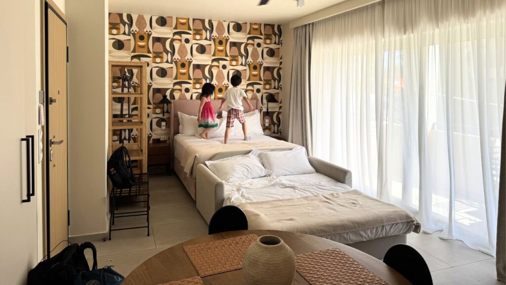 コウカキ地区のモダンなアパートメントホテルの客室でベッドで遊ぶ子どもたち