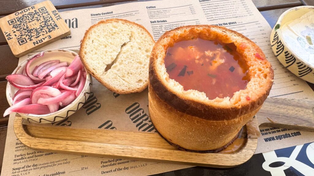 くり抜いたパンの器に注がれた豆と燻製肉のスープ