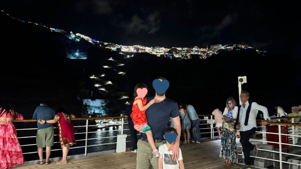 甲板からサントリーニ島の夜景を眺める家族