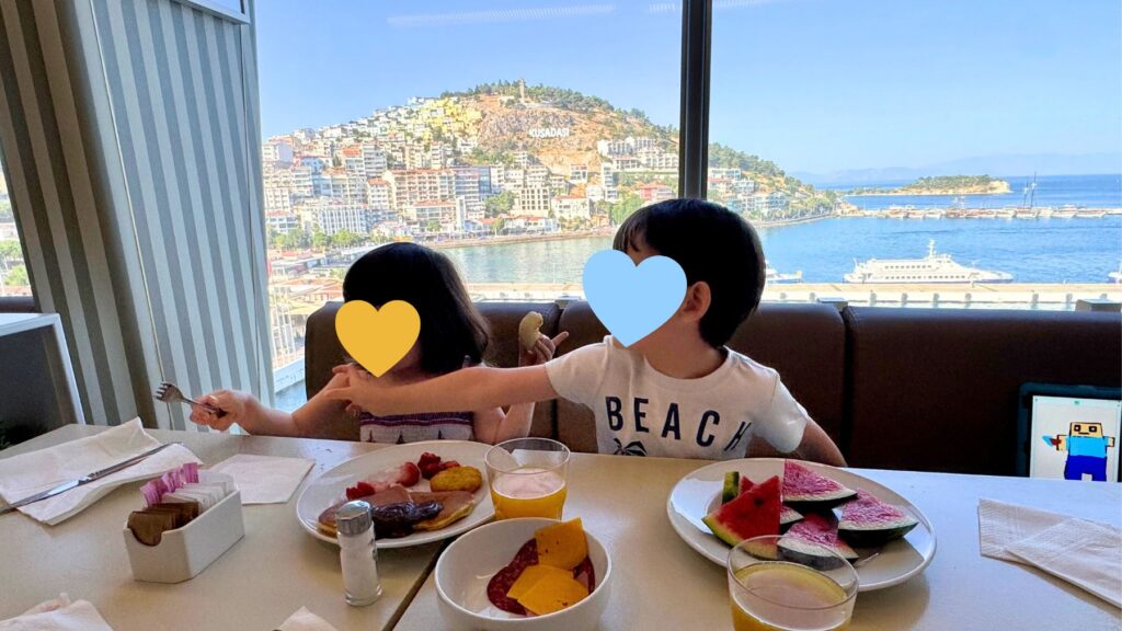 窓の向こうにトルコ・クシャダスの街並みを望むダイニングで朝食をとる子どもたち
