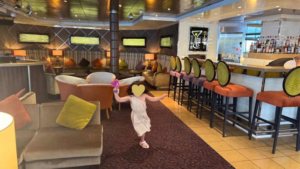 Martini Bar & Loungeを歩く娘。カラフルなバースツールが並ぶ店内
