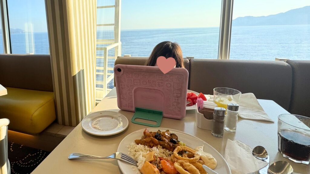 海を望むレストランでタブレットを見ながら過ごす子ども