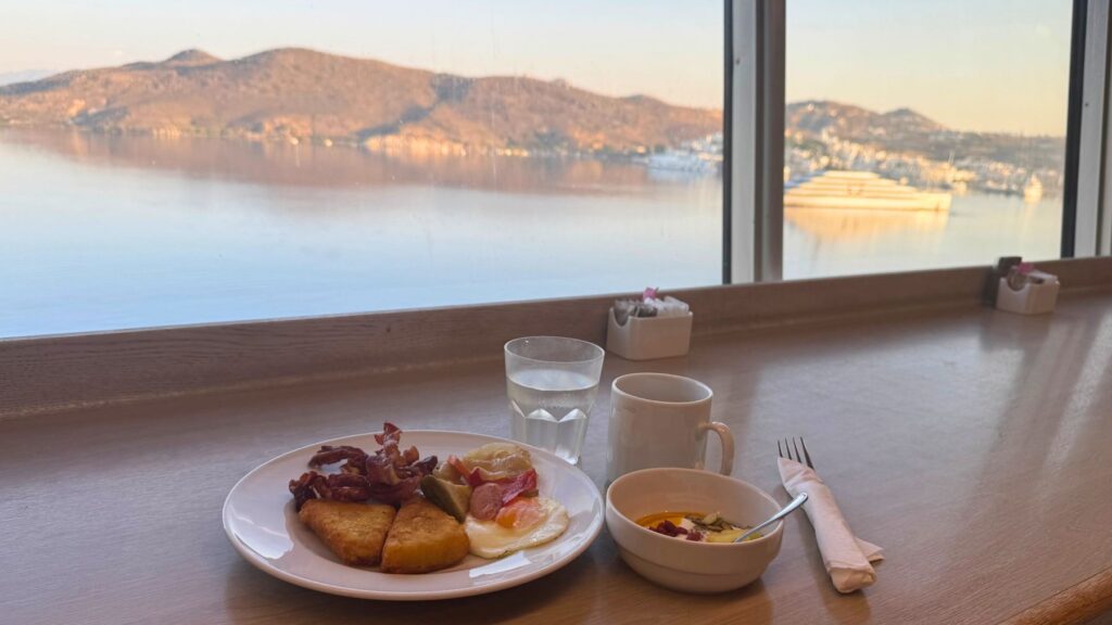 ミロス島を望むThe Tavernaの窓辺での朝食。ベーコン・ハッシュドポテト・目玉焼き・ヨーグルトとコーヒー