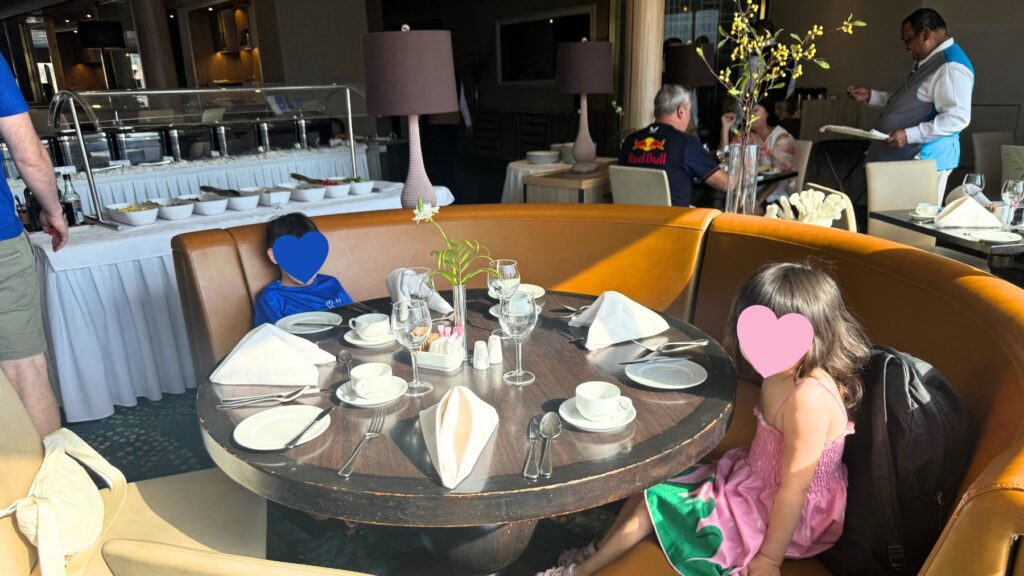 Thalassa Restaurantの座席。丸テーブルに着いた子どもたち、奥に朝食ビュッフェ