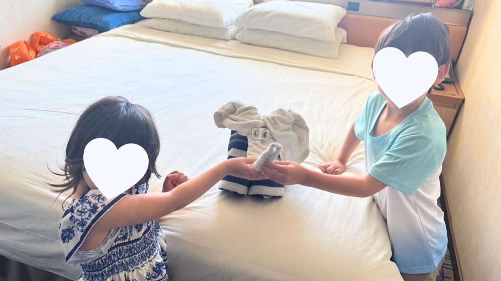 客室のベッドに置かれたタオルアートのゾウを受け取る子どもたち