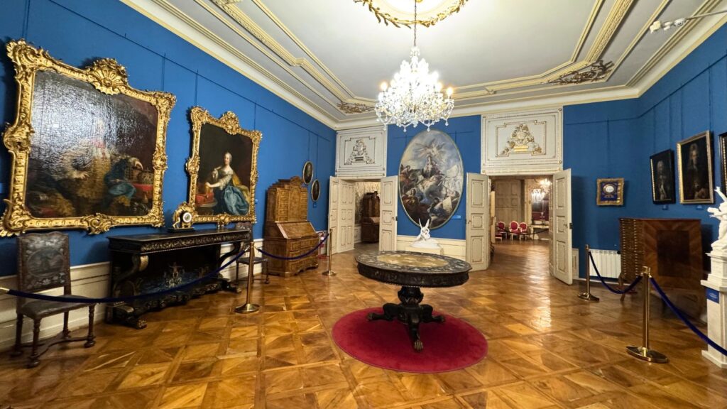 ブルケンタール国立博物館の青い壁の展示室。金の額縁に入った肖像画とシャンデリア、寄木張りの床