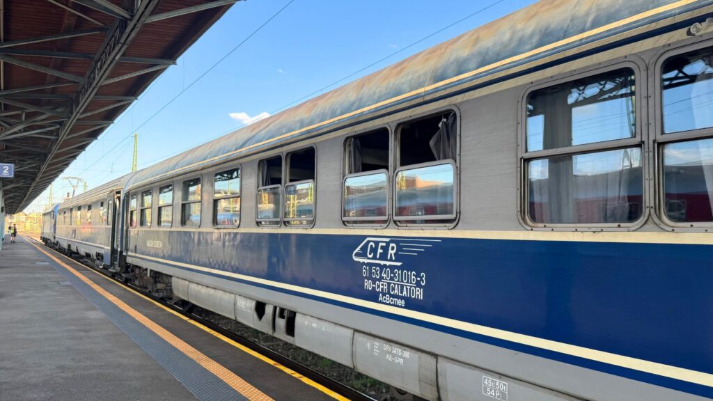 駅のホームに停まるルーマニア国鉄CFRの寝台車両。青とグレーの車体に「CFR」のロゴ