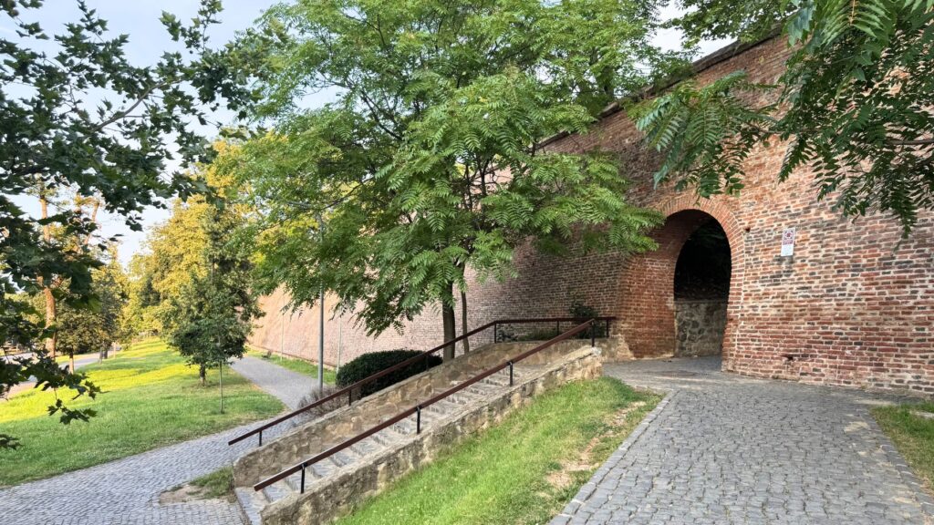 シビウの城壁に開いたれんがのアーチ門。緑の木立と、公園側から続く石畳の坂道