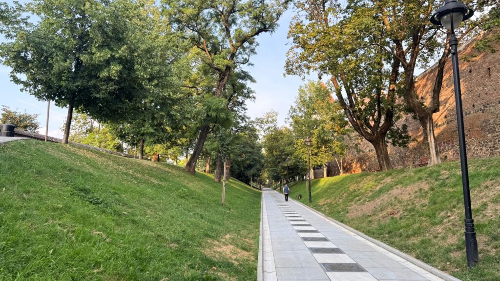 シビウの城壁沿いに続く公園の遊歩道。芝生の土手と並木、朝の散歩をする人