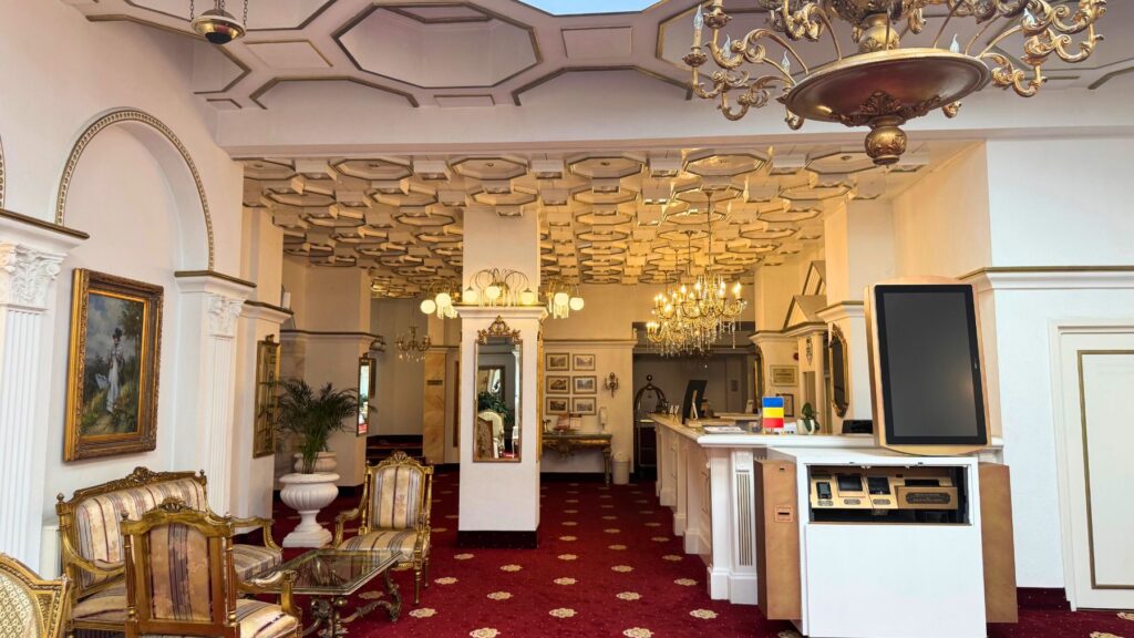 Hotel Împăratul Romanilor のロビーと受付。赤い絨毯と格天井、金のシャンデリア、クラシックな家具
