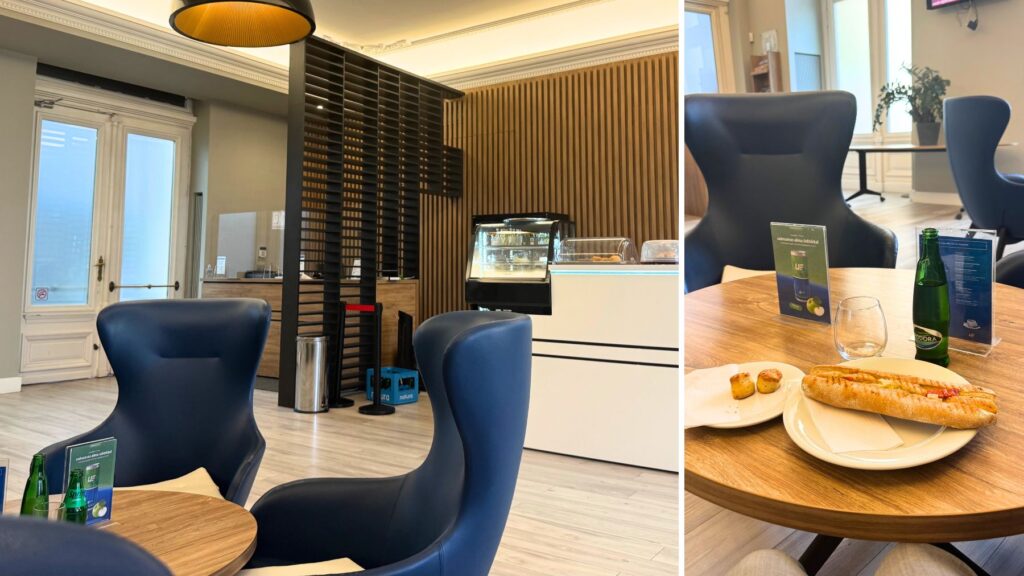 ブダペスト東駅のプレミアムラウンジ。紺色のハイバックチェアと木目の内装、ドリンクの冷蔵ケース、テーブルにはサンドイッチと飲み物
