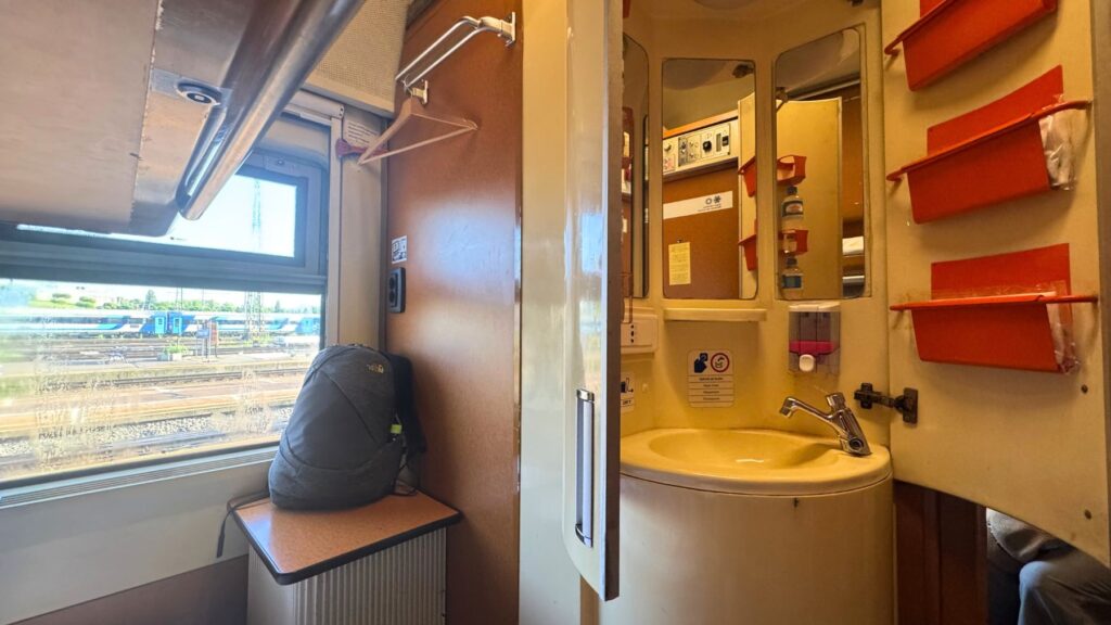 夜行列車の個室に付いた洗面台。鏡とオレンジ色の小物入れ、水圧は低め