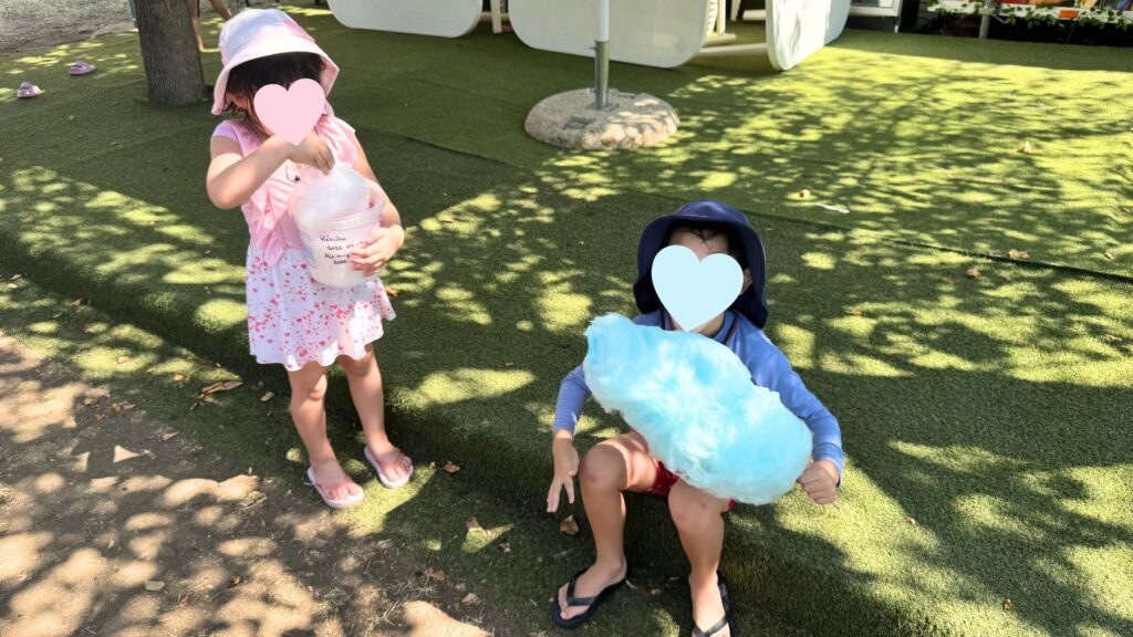 エゲルのスパの木陰の芝生で、水色とピンクの綿菓子を持つ子どもたち