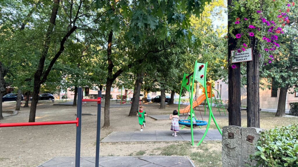 美女の谷のセラーに囲まれた緑地にある子どもの遊具。ブランコで遊ぶ子どもたち