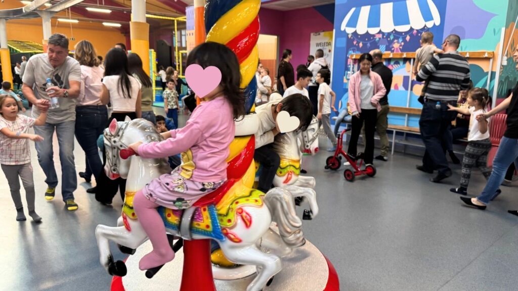 メリーゴーラウンドの木馬に乗る子どもたち