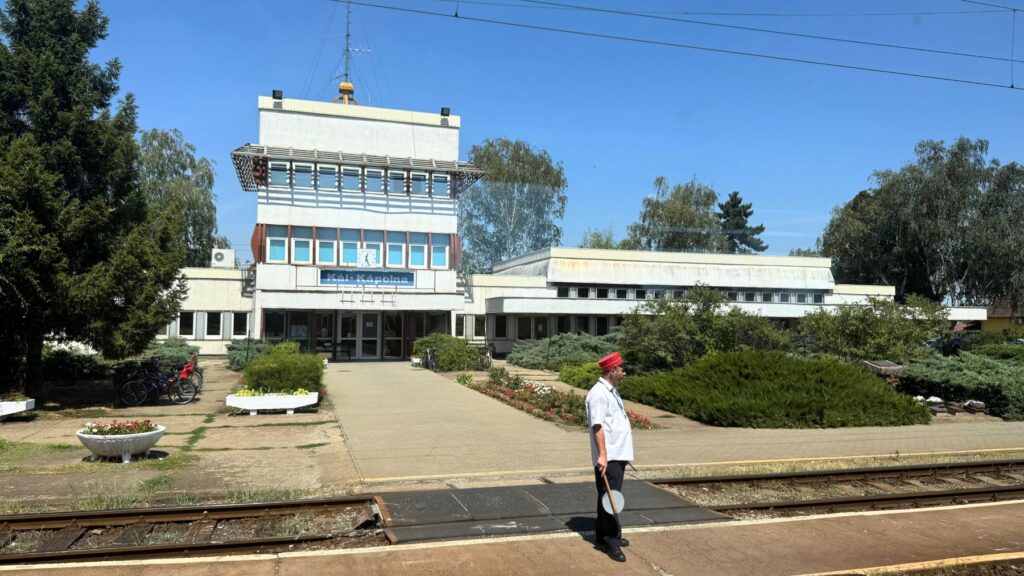ハンガリーの地方の駅と、赤い帽子をかぶった駅員。夏の日差しの強いホーム