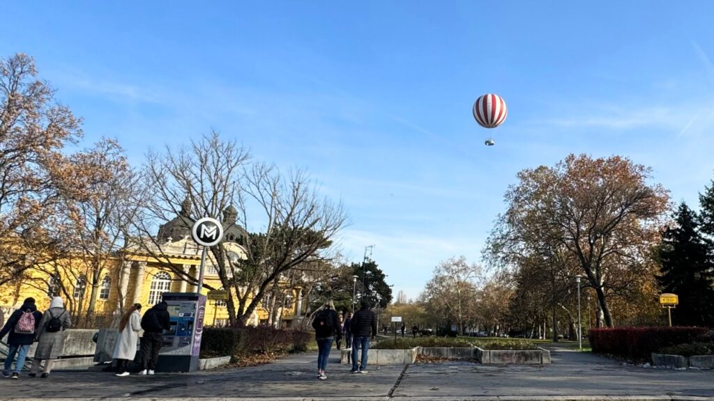 ブダペストの市民公園で木々の上の青空に浮かぶ赤と白の縞模様の気球