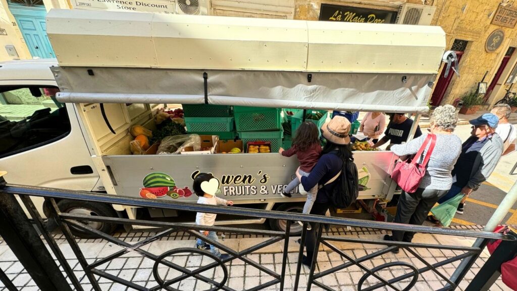 ビルグの路上に出ていた野菜や果物の移動販売車で、地元の人たちに混じって買い物する家族。