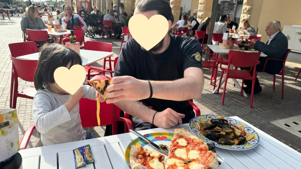 スリーマのショッピングモールThe Point前のイタリアンのテラス席で、ピザやムール貝を食べる家族。