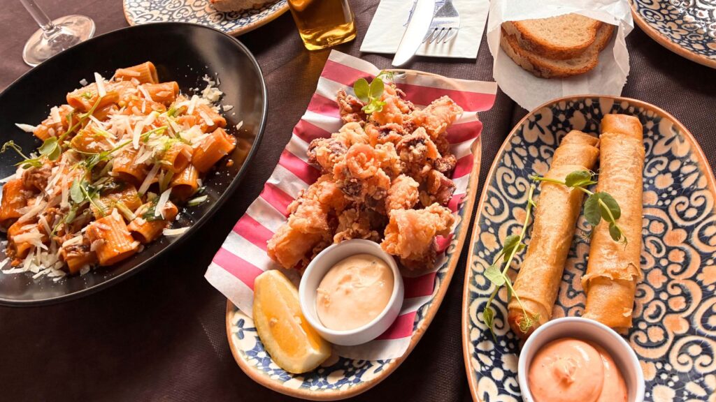 バレッタのLa Pira Maltese Kitchenでの食事。左にチーズをのせたパスタ、中央にイカの揚げ物、右に細長いラビットロールが並ぶ。