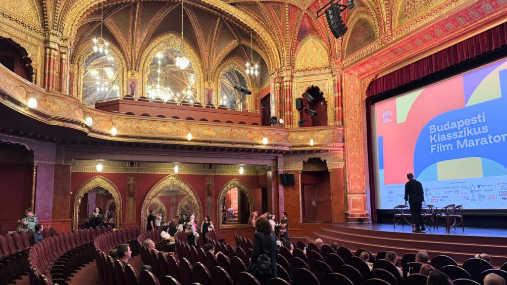 映画祭名が映るウラーニア国立映画館のスクリーンと舞台、観客が集まる客席