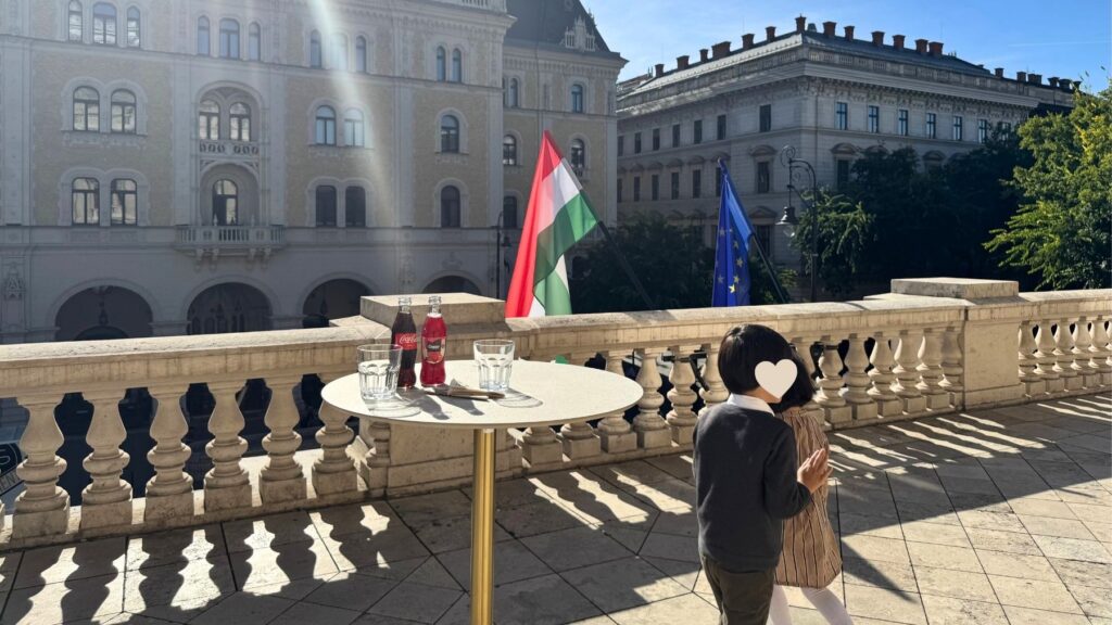 ブダペストのオペラ座のテラスで過ごす子どもたちと、ドリンクを置いたテーブル、通りの向かいの建物