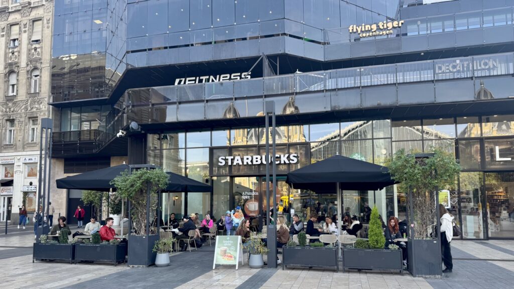 ブダペスト西駅の向かいにあるスターバックス・ニュガティの外観と、利用客でにぎわうテラス席