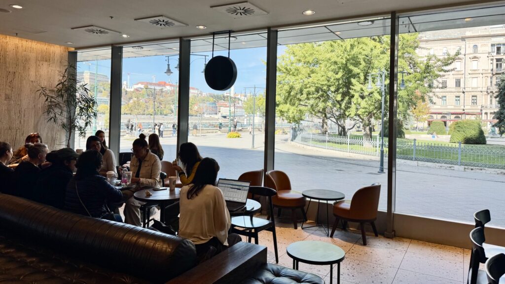 スターバックス・プロムナードの店内と、大きな窓から見える川沿いの遊歩道やブダ側の景色