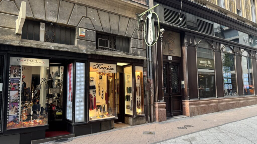 ネクタイ形の看板と明るいショーウィンドウがあるKacziánの店舗外観