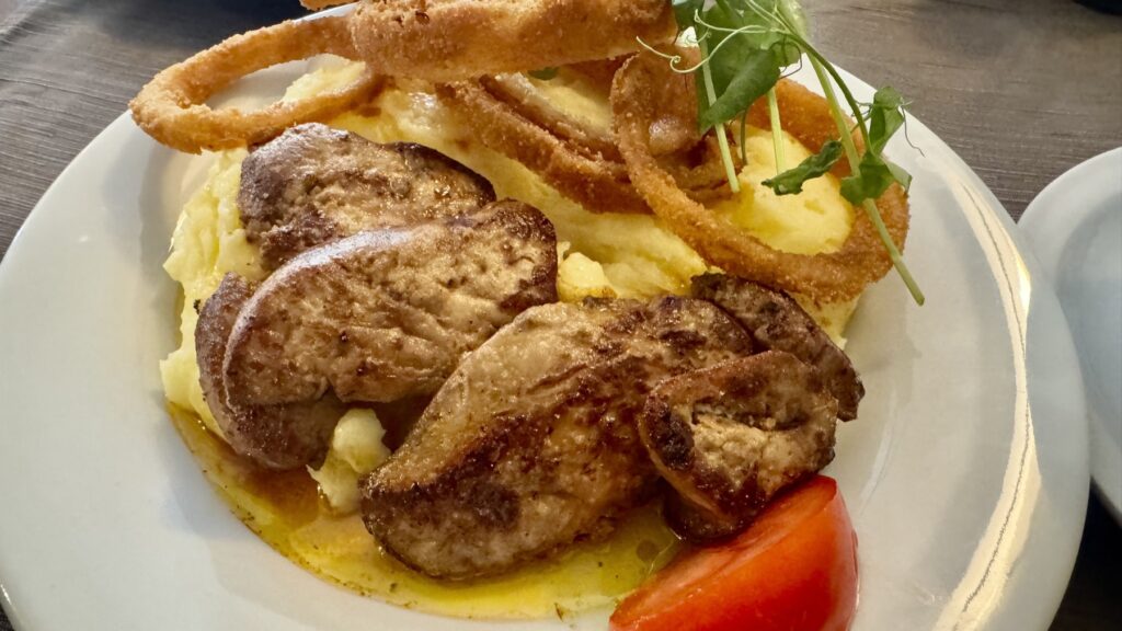 マッシュポテトの上に盛られたKék Rózsaの焼きフォアグラとオニオンリング